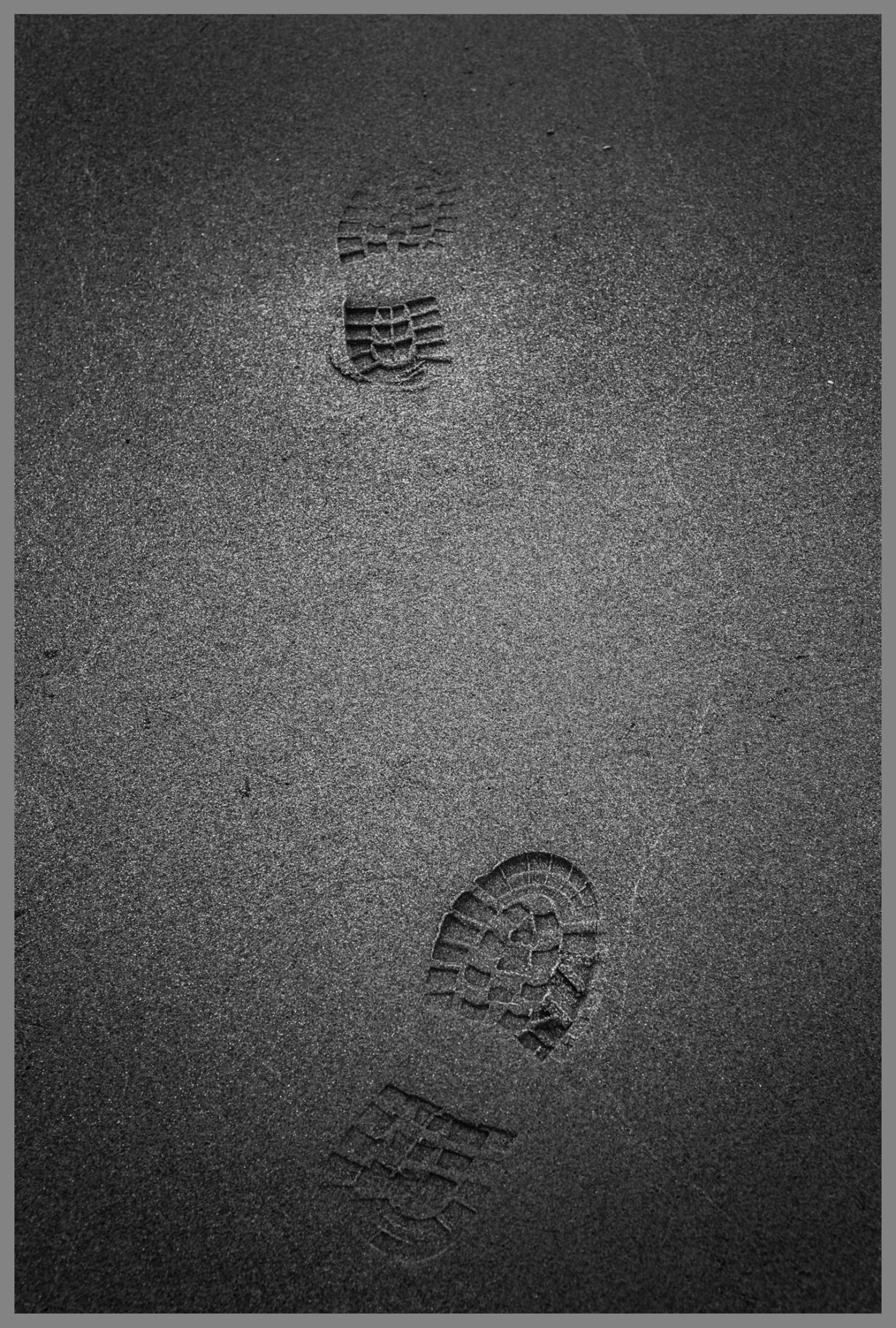 Schwarzweiße Fußabdrücke im Sand